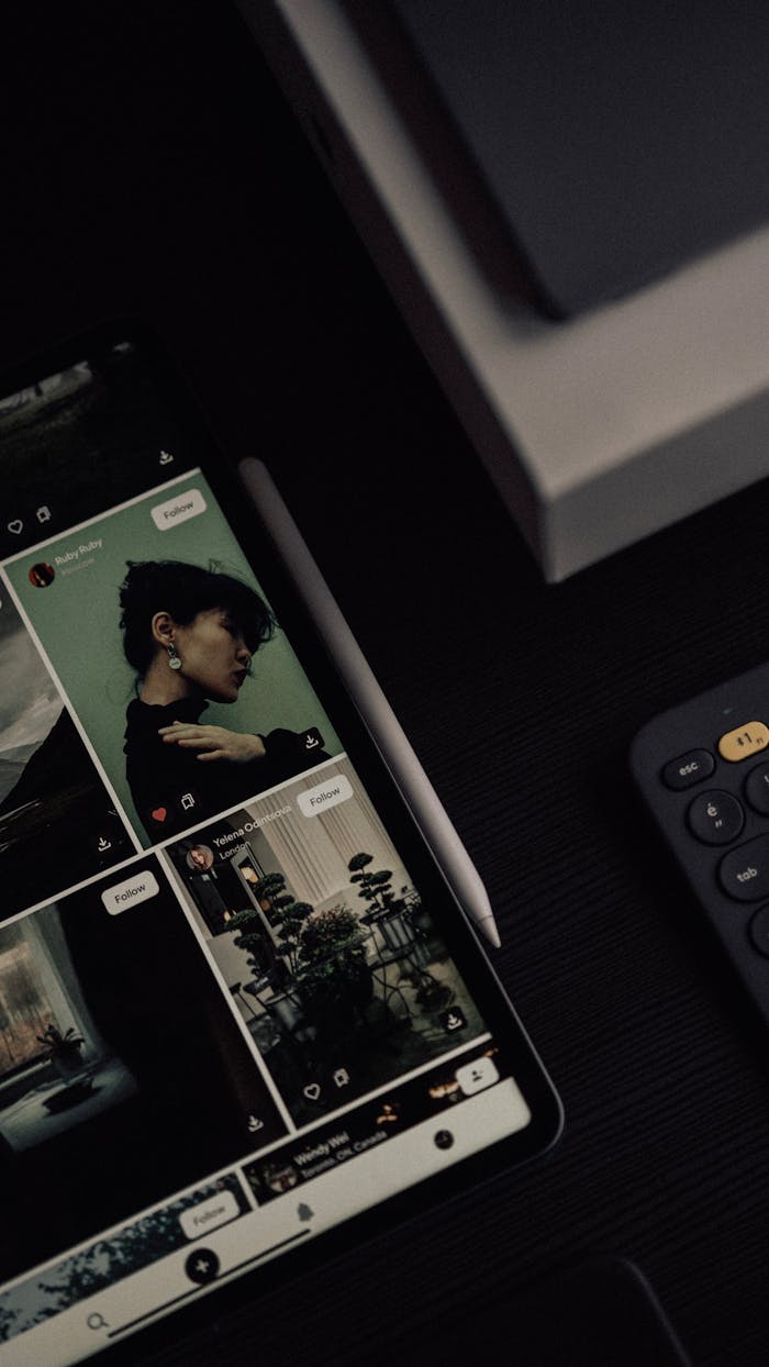 Modern workspace with digital tablet and keyboard featuring social media photos.